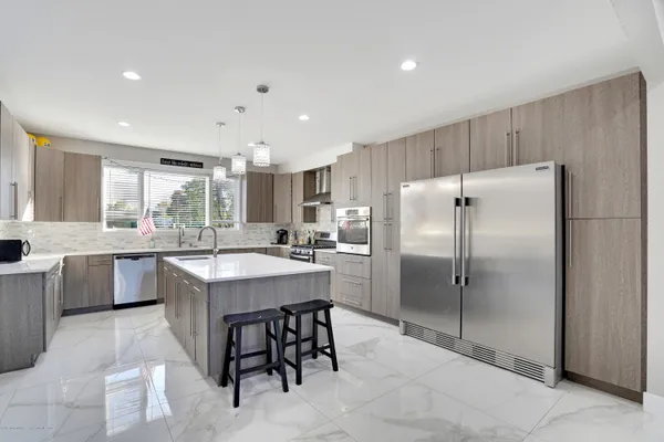 a kitchen with kitchen island granite countertop a refrigerator a sink a stove a dining table and chairs