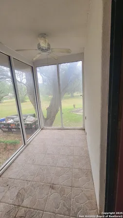 a view of empty room with wooden floor and fan
