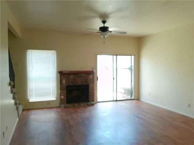 an empty room with wooden floor a ceiling fan and a fireplace