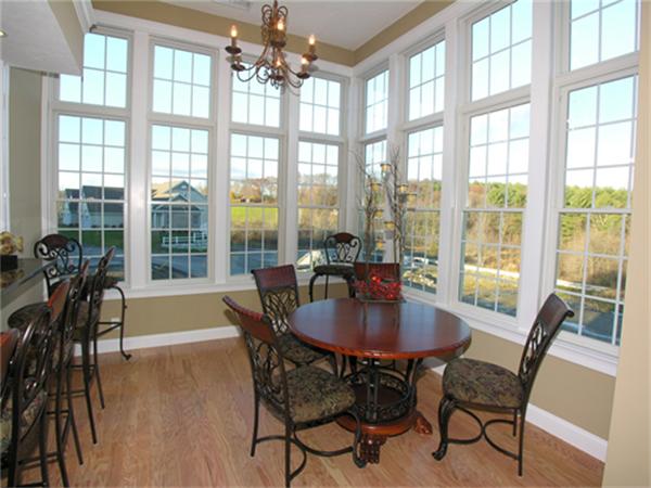 705 Autumn Ridge Drive, Unit 705 Ayer, MA 01432 - Photo 14 of 16 a dining room with furniture large windows and wooden floor