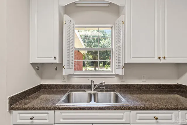 a kitchen with granite countertop a sink dishwasher and cabinets next to a window