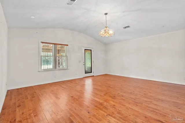a view of an empty room with window and wooden floor