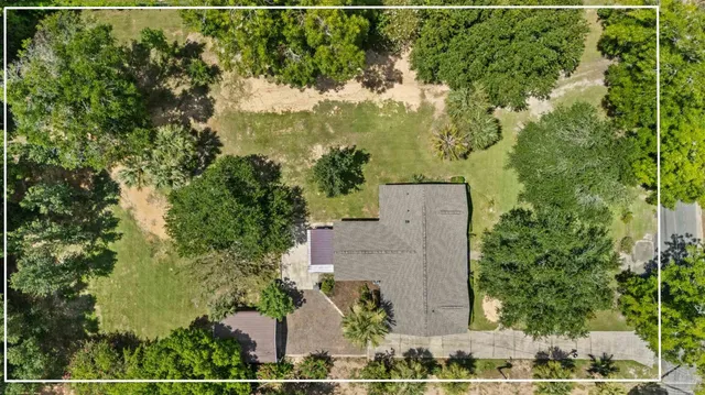 an aerial view of a residential houses with outdoor space and trees all around