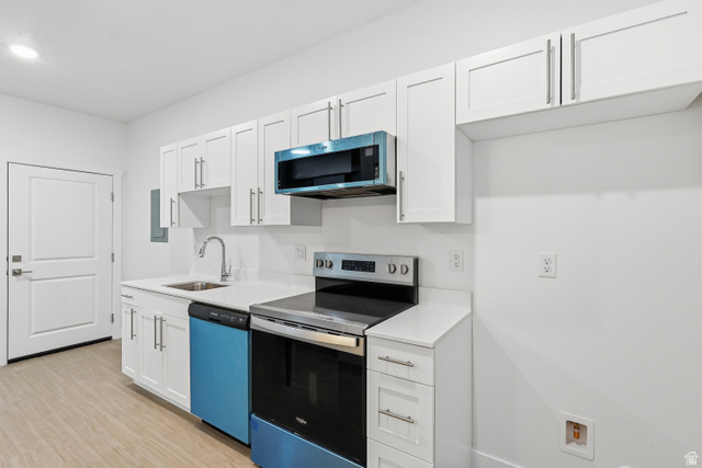 2085 North Main Street, Unit 409 Sunset, UT 84015 - Photo 3 of 17 Kitchen with stainless steel appliances, white cabinets, and light wood-style floors