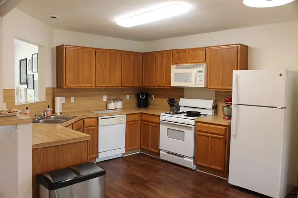 a kitchen with a refrigerator stove and sink with wooden floor