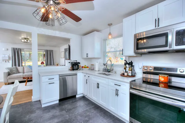 a kitchen with a sink dishwasher stove and white cabinets
