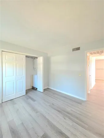 an empty room with wooden floor & windows