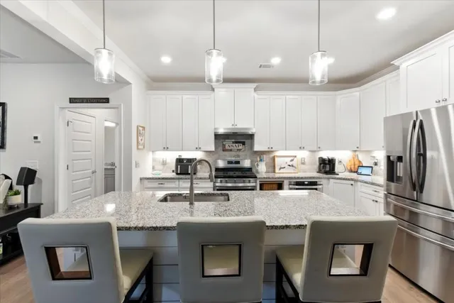 a kitchen with stainless steel appliances granite countertop a stove a refrigerator a kitchen island a sink and a refrigerator