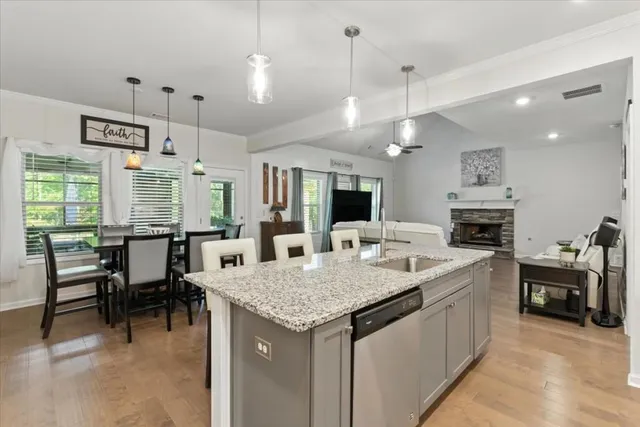 a kitchen with granite countertop a stove a sink a dining table and chairs