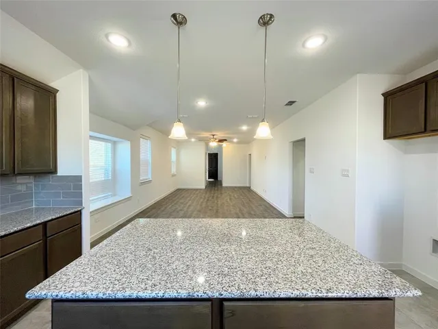 a view of a kitchen with kitchen island a sink wooden floor and a counter top space