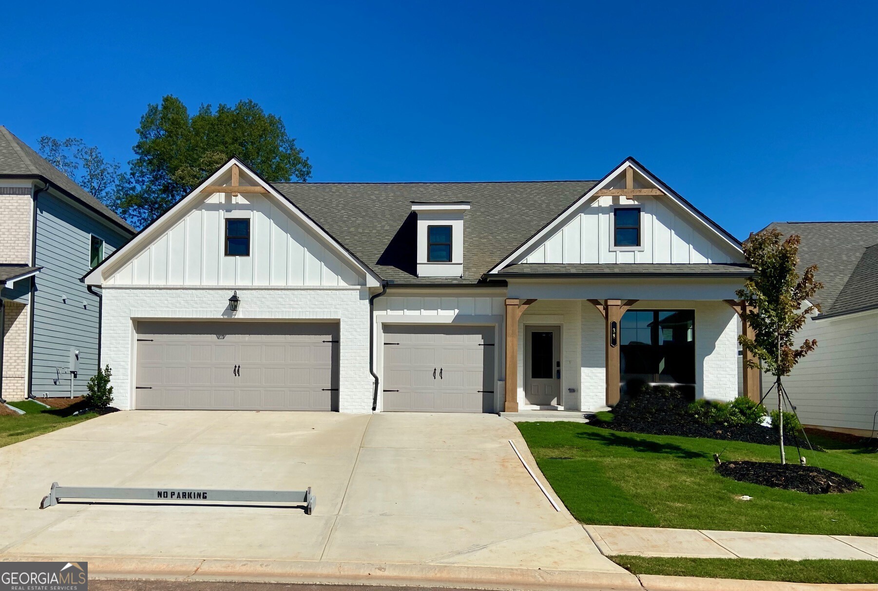 a view of a white house with a small yard and a large tree
