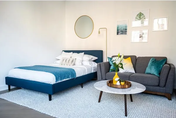 a bedroom with a bed a couch and a potted plant