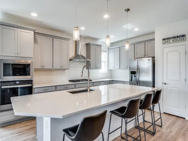 a kitchen with stainless steel appliances a table chairs refrigerator and cabinets