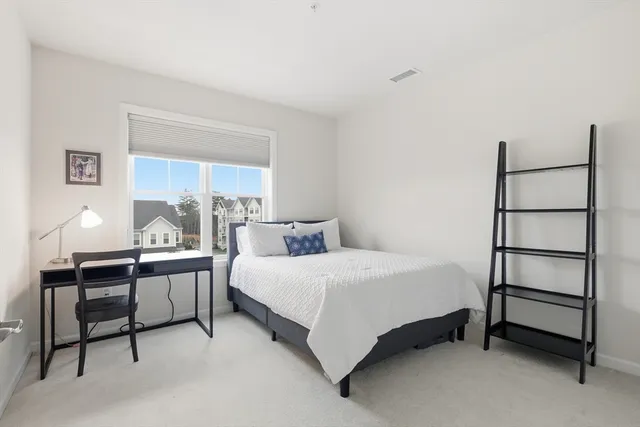 a bedroom with a bed table lamp and a window