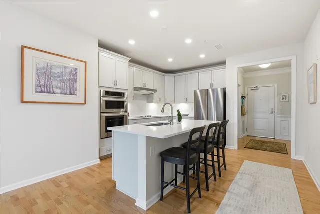a kitchen with stainless steel appliances a dining table chairs and refrigerator