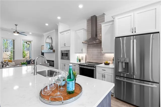 a kitchen with stainless steel appliances granite countertop a refrigerator a sink a stove and chairs with wooden floor