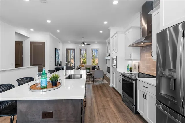 a large kitchen with stainless steel appliances a large center island attached withe living room