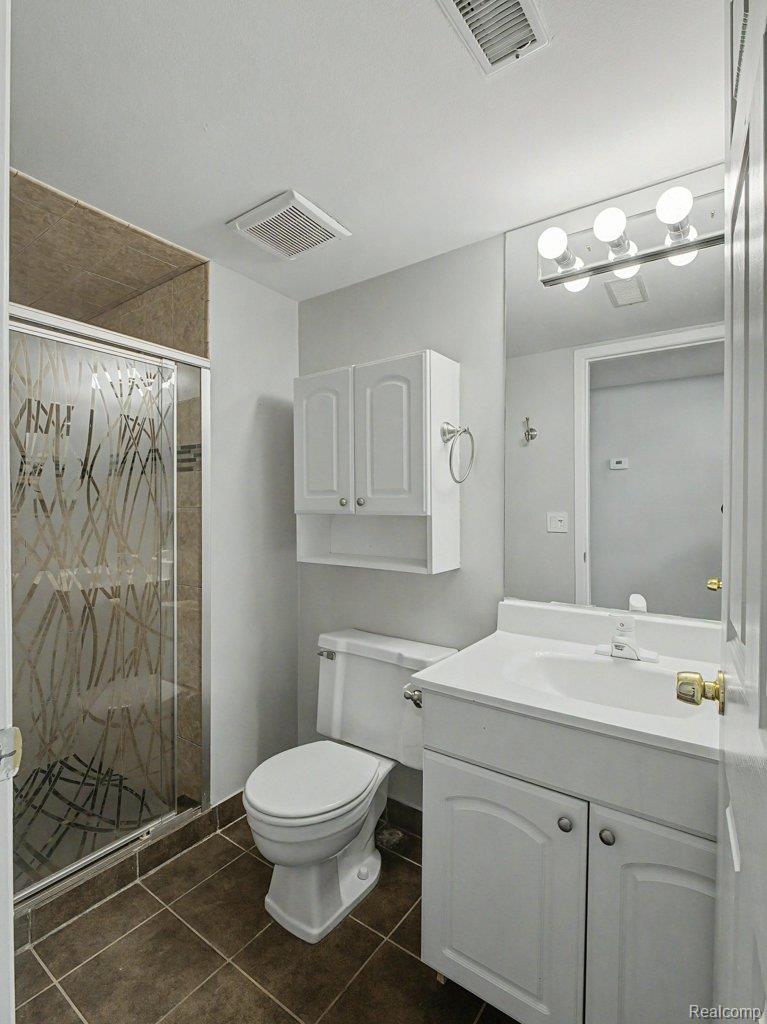 1974 Klingensmith Road, Unit 4 Bloomfield Hills, MI 48302 - Photo 16 of 35 Bathroom featuring a shower enclosure with patterned glass, white vanity with integrated sink, coordinating white cabinetry, and large format tile flooring