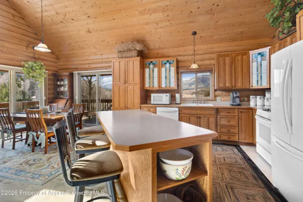a kitchen with stainless steel appliances kitchen island granite countertop a table chairs sink and cabinets