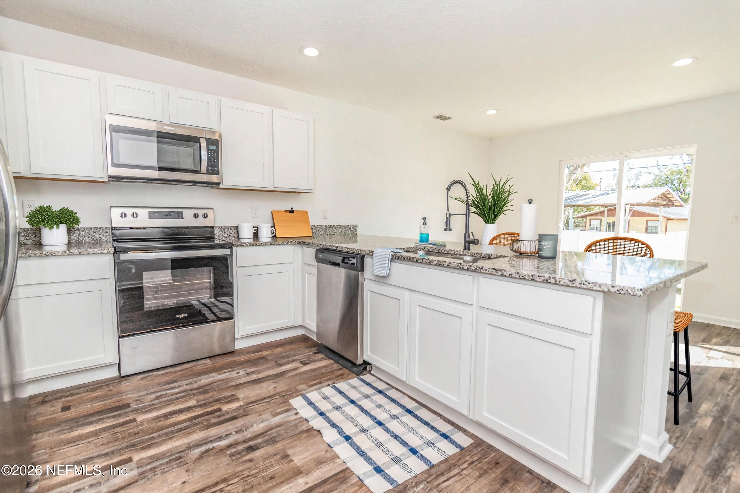768 Constitution Place Macclenny, FL 32063 - Photo 8 of 41 a kitchen with stainless steel appliances granite countertop a stove a sink and a microwave