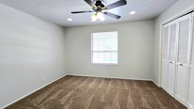 8732 Fairoaks Circle Sandy, UT 84070 - Photo 14 of 18 Unfurnished bedroom featuring a closet, dark colored carpet, a ceiling fan, and recessed lighting