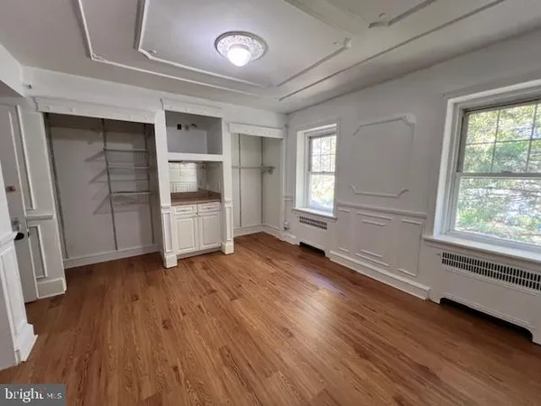 an empty room with wooden floor closet and windows