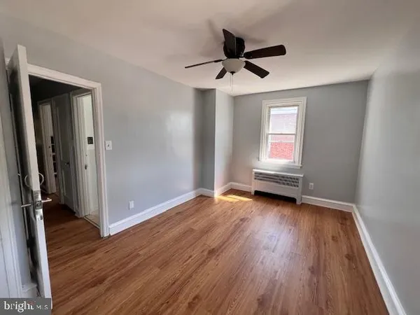 a view of empty room with wooden floor and fan