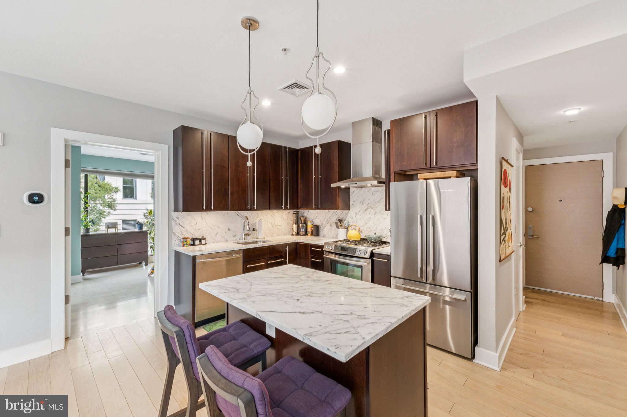 1634 14th Street Northwest, Unit 201 Washington, DC 20009 - Photo 5 of 21 a kitchen with stainless steel appliances a table chairs and refrigerator