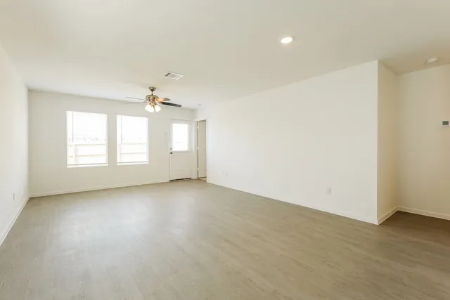 an empty room with wooden floor and windows