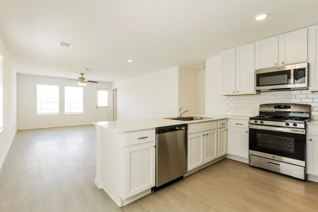 a kitchen with stainless steel appliances granite countertop a stove a sink and a microwave