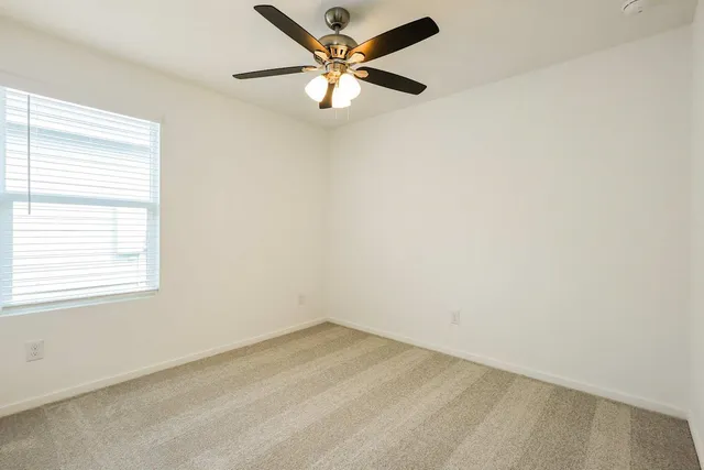 an empty room with a window and a ceiling fan