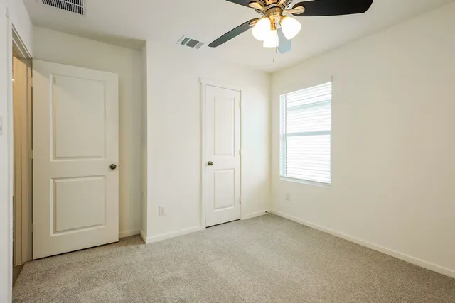 an empty room with a chandelier fan and windows