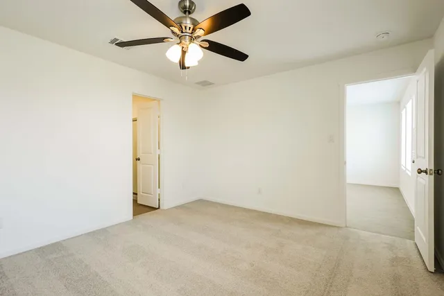 an empty room with a ceiling fan and a fan