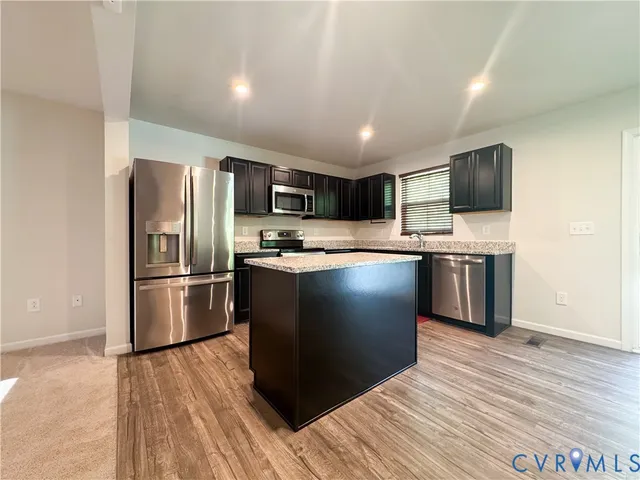 a kitchen with granite countertop a refrigerator and a stove top oven
