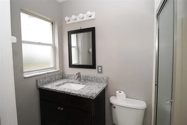 a bathroom with a granite countertop sink toilet and mirror