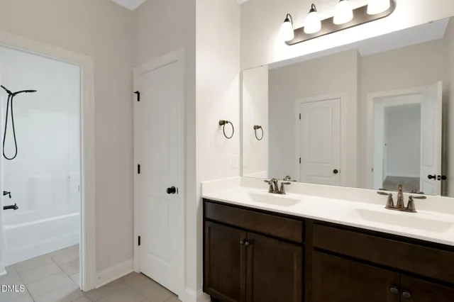 a bathroom with a double vanity sink a tub and a mirror