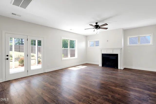 an empty room with wooden floor fireplace and windows