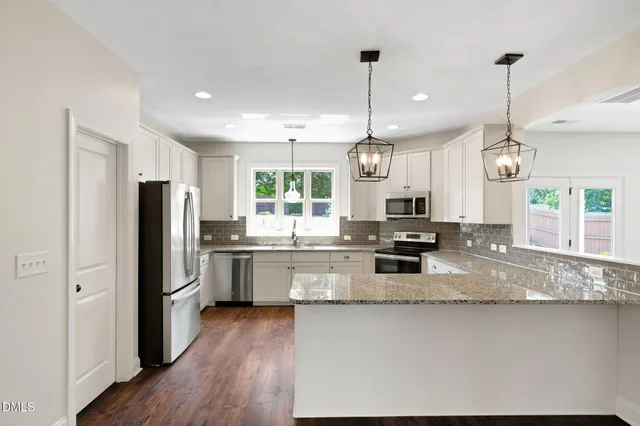 a large kitchen with stainless steel appliances kitchen island granite countertop a refrigerator a stove a sink dishwasher a dining table and chairs with wooden floor