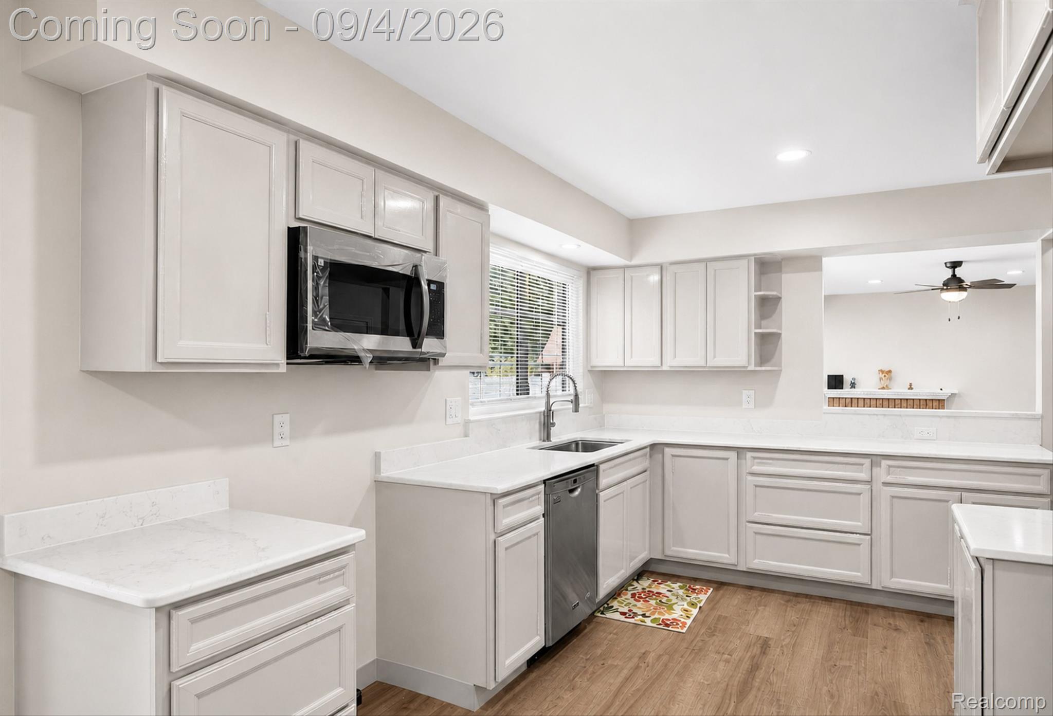 43182 Applewood Road Canton, MI 48188 - Photo 10 of 36 Kitchen featuring light-toned cabinetry, white countertops, wood-finish flooring, stainless steel microwave, and integrated dishwasher