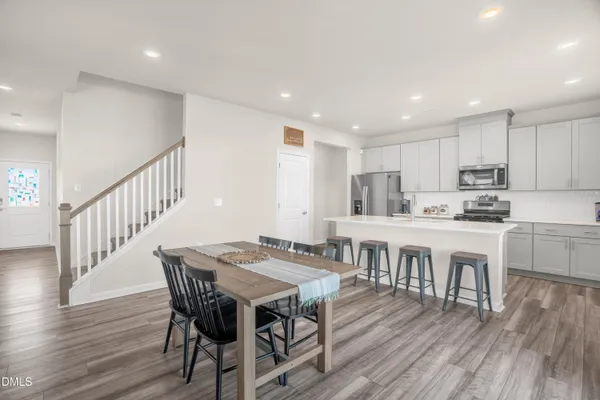 a kitchen with kitchen island a dining table chairs and white cabinets