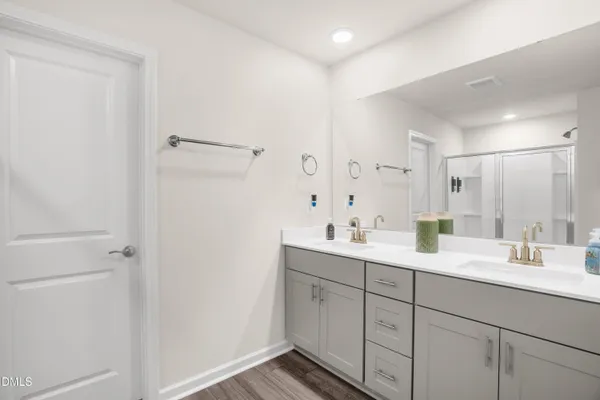a spacious bathroom with a double vanity sink a mirror and a shower
