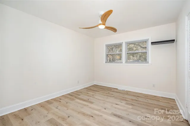 an empty room with wooden floor and ceiling fan