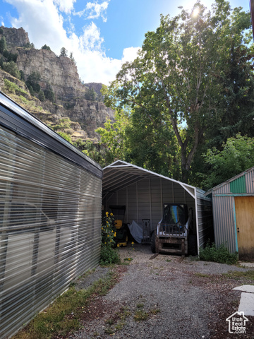 97 East Main Street Stockton, UT 84071 - Photo 24 of 58 View of parking with a carport, gravel driveway, a mountain view, and a storage shed