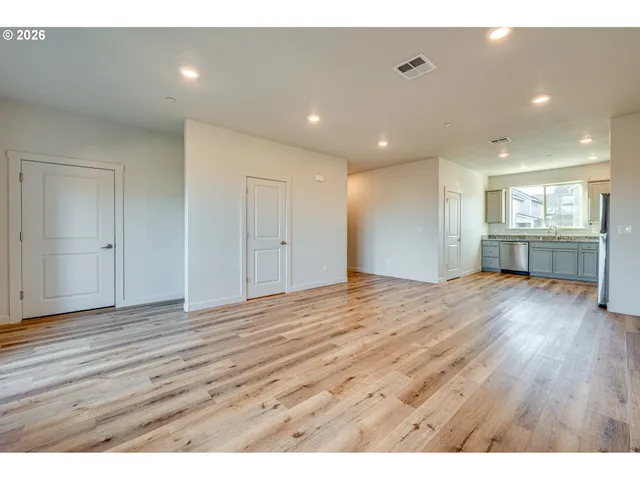 a view of an empty room with wooden floor and window