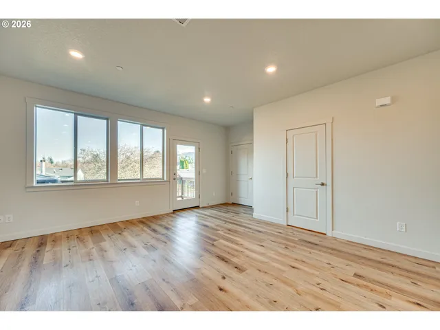 a kitchen with stainless steel appliances granite countertop a stove a sink dishwasher a refrigerator and white cabinets with wooden floor