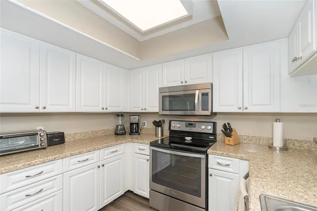 a kitchen with stainless steel appliances granite countertop a sink a stove a microwave and cabinets