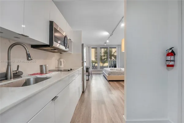 a view of a kitchen with kitchen island a sink a counter space stainless steel appliances and cabinets