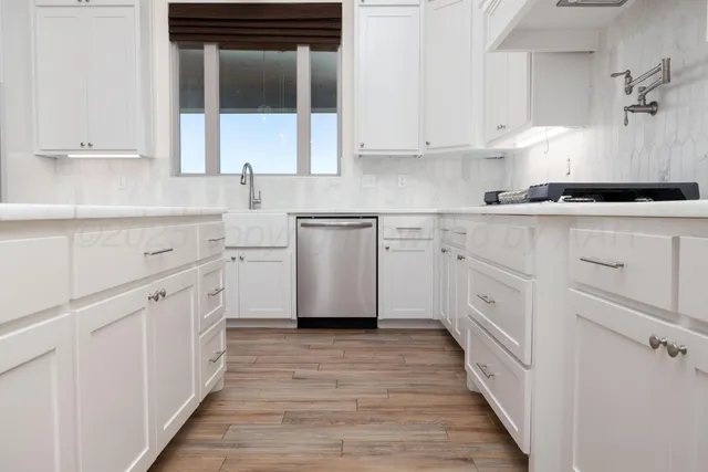 a kitchen with white cabinets appliances and a sink