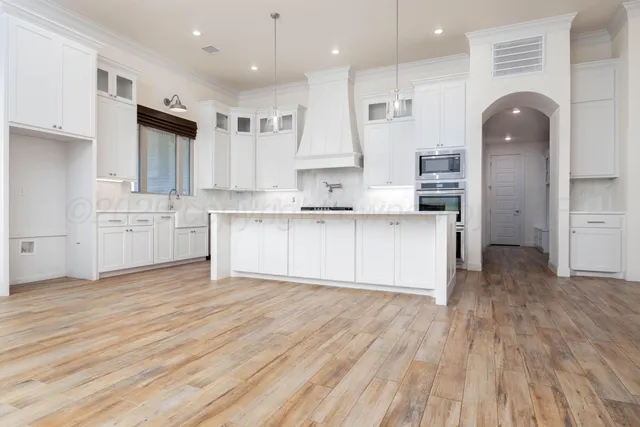 a large kitchen with cabinets wooden floor and stainless steel appliances