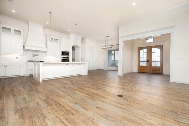 a large white kitchen with cabinets and wooden floor